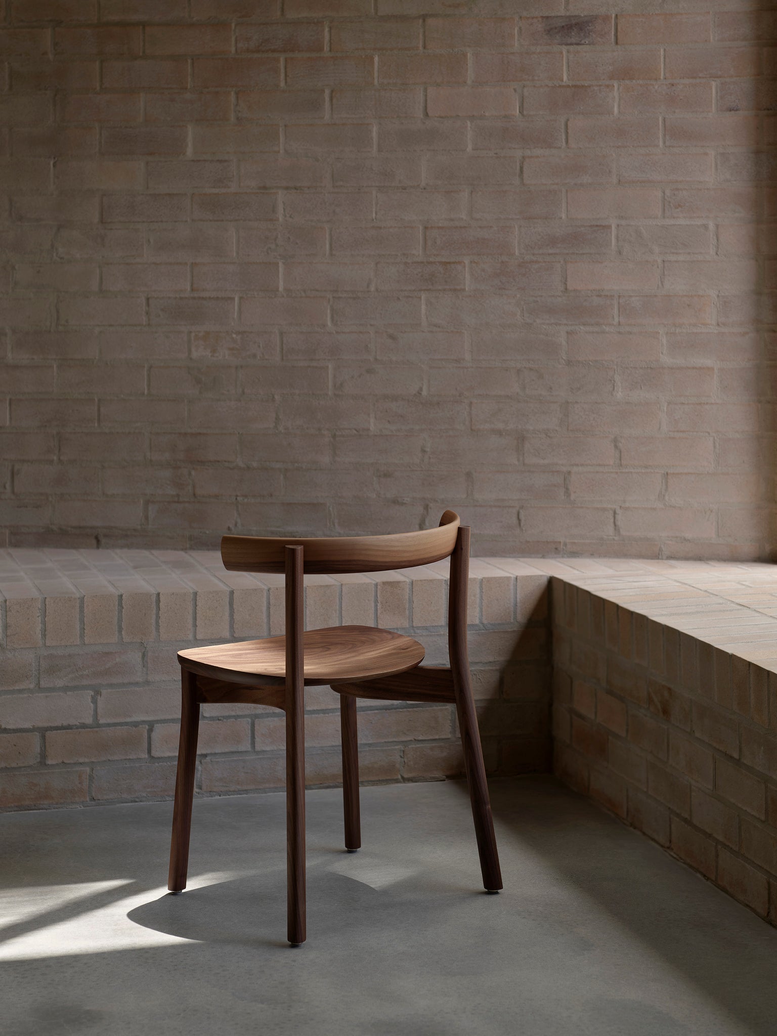 Torii chair in walnut with brick background