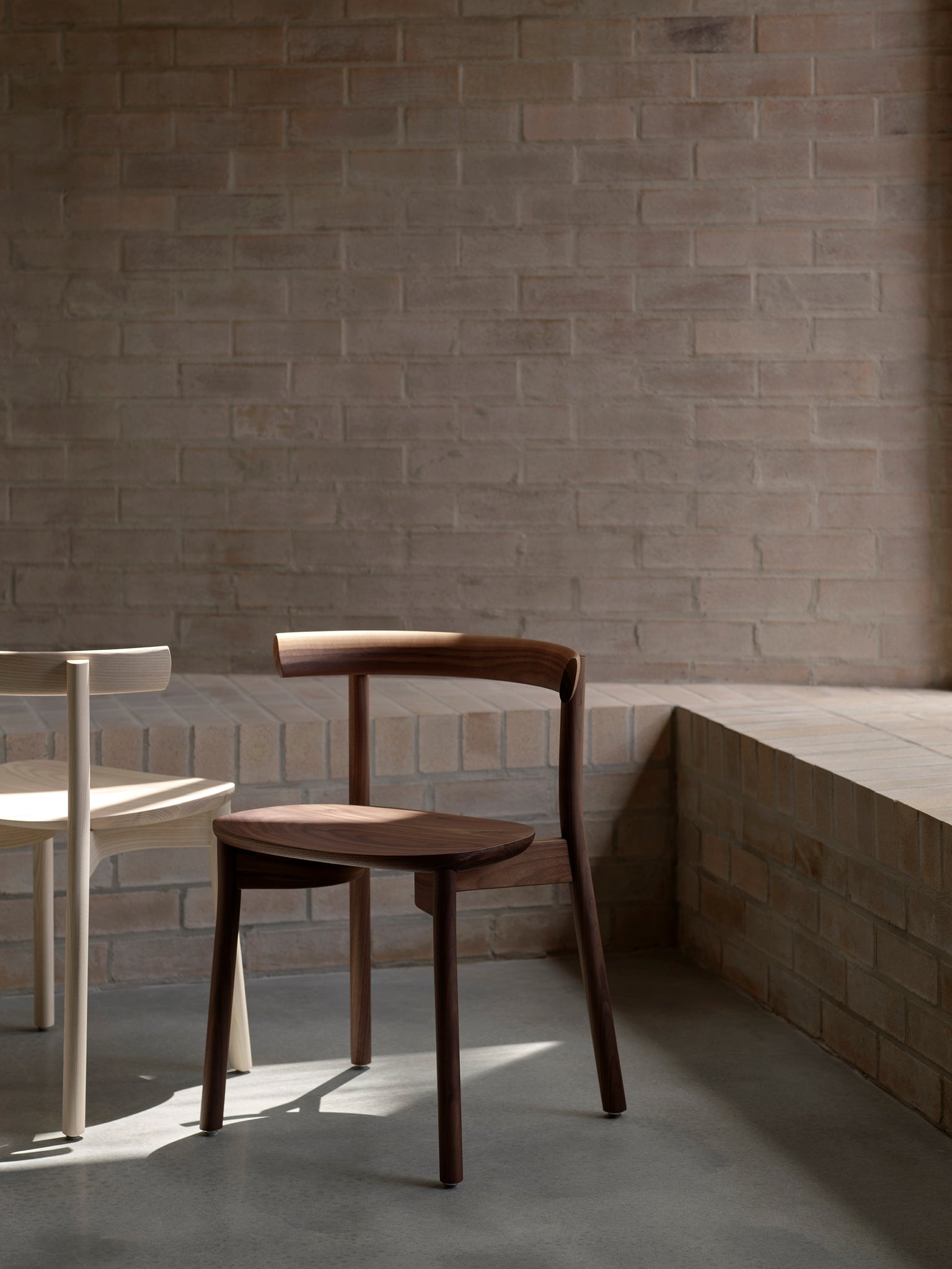 Torii chairs in walnut and white ash with brick background